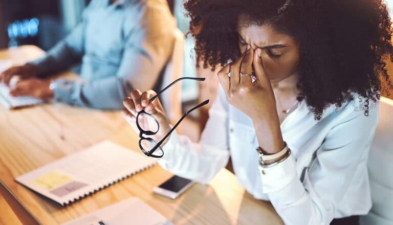 Young office worker experiencing eye discomfort at laptop computer