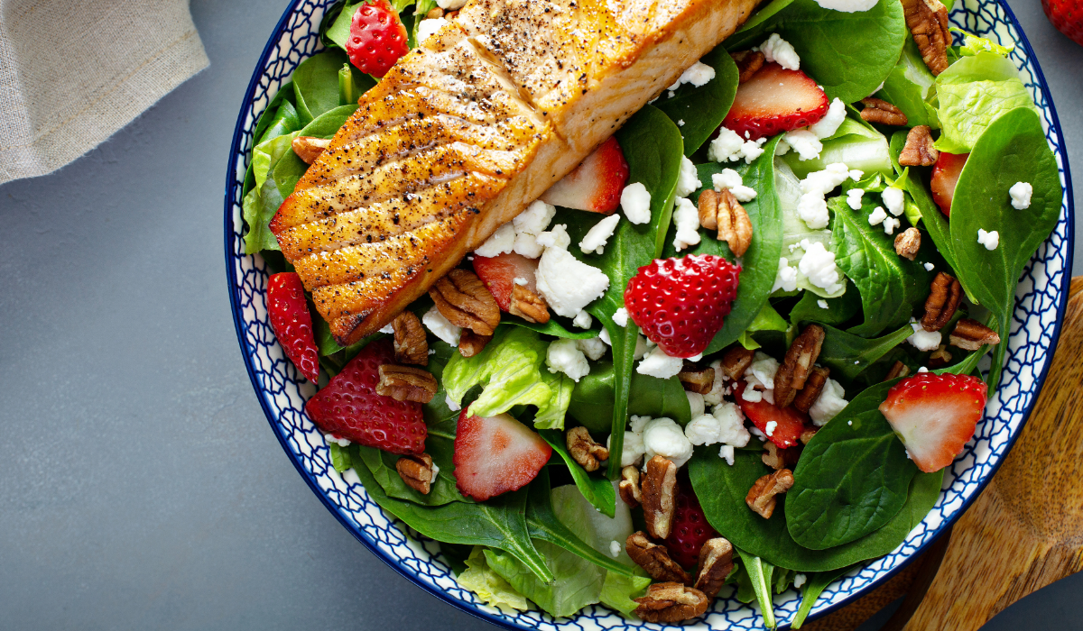 An eye healthy salad with green leafy greens, fish, berries, and peacans.