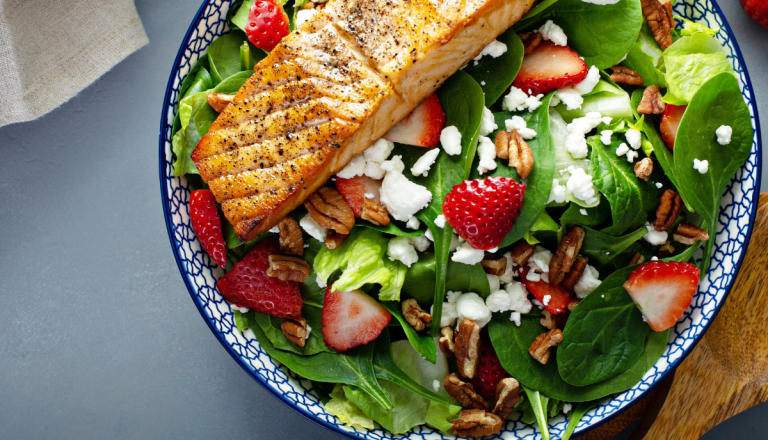 An eye healthy salad with green leafy greens, fish, berries, and peacans.